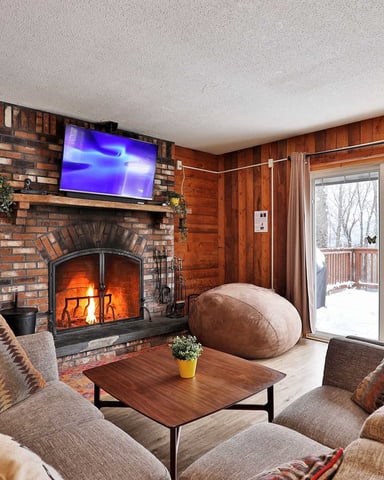 Cozy living room with a brick fireplace and winter views through the patio door.